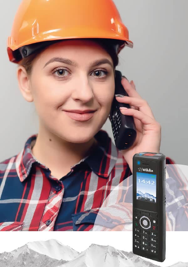 Ouvrière souriante avec un casque de chantier au téléphone